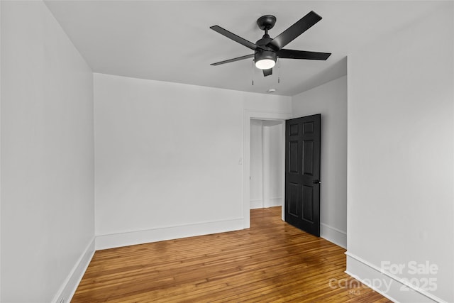 spare room with a ceiling fan, wood finished floors, and baseboards