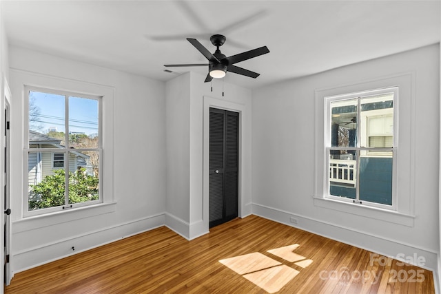 unfurnished bedroom with light wood-style flooring, baseboards, a closet, and ceiling fan