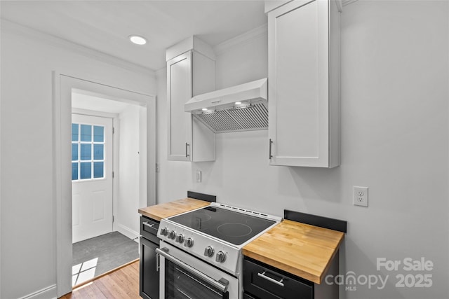 kitchen with electric range, butcher block countertops, light wood-style flooring, ventilation hood, and white cabinets