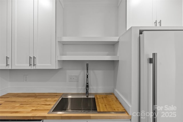 kitchen with crown molding, white fridge, white cabinets, wood counters, and open shelves