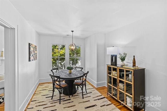 dining space featuring baseboards, an inviting chandelier, and wood finished floors