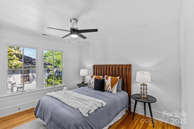 bedroom with visible vents, baseboards, a ceiling fan, and wood finished floors