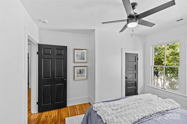 bedroom with wood finished floors, baseboards, a ceiling fan, and visible vents