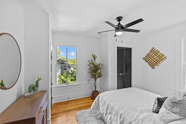bedroom with baseboards, light wood finished floors, and a ceiling fan