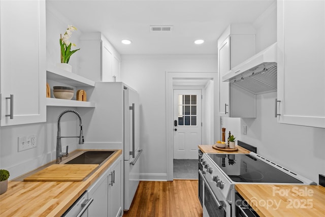 kitchen with butcher block countertops, white cabinetry, stainless steel electric stove, and open shelves
