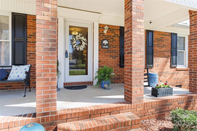 doorway to property featuring brick siding and covered porch