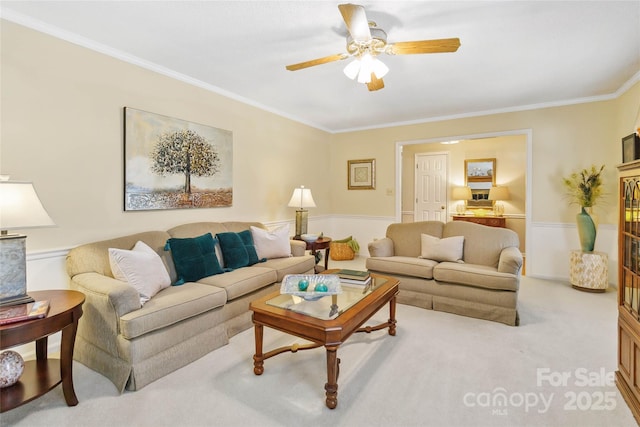 living room with ceiling fan, ornamental molding, and carpet flooring