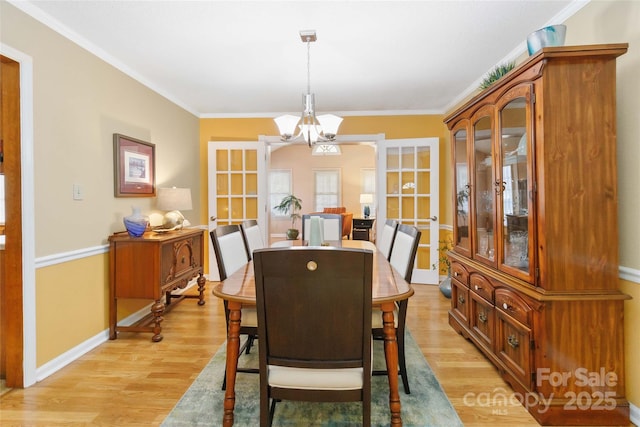 dining space with baseboards, light wood-style floors, an inviting chandelier, and ornamental molding