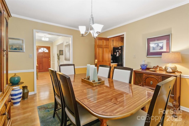 dining space featuring light wood-style floors, baseboards, a chandelier, and ornamental molding