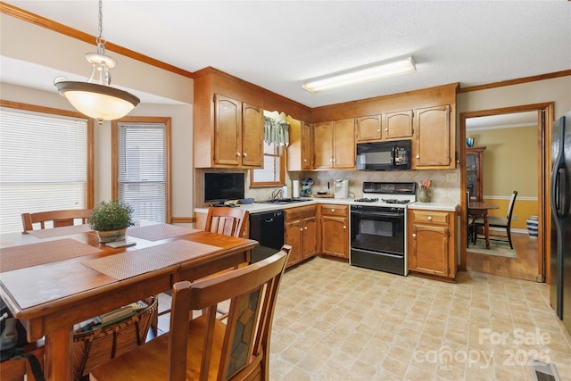 kitchen with a sink, black appliances, light countertops, crown molding, and backsplash