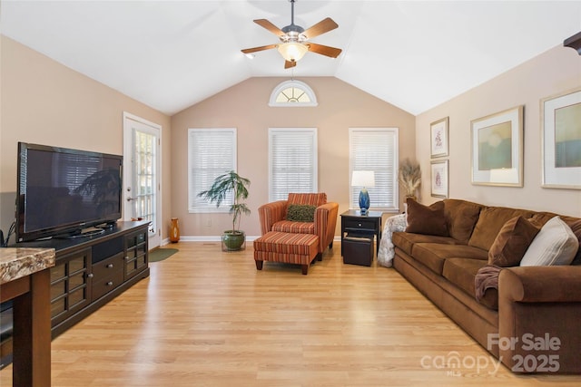 living area with ceiling fan, baseboards, light wood-style floors, and vaulted ceiling