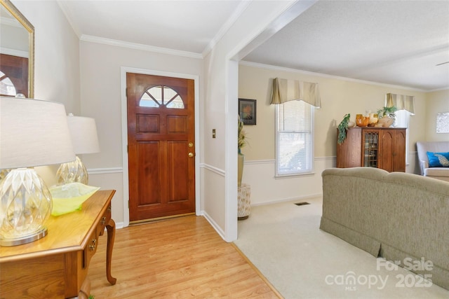 foyer entrance featuring a wealth of natural light, visible vents, crown molding, and light wood-style floors