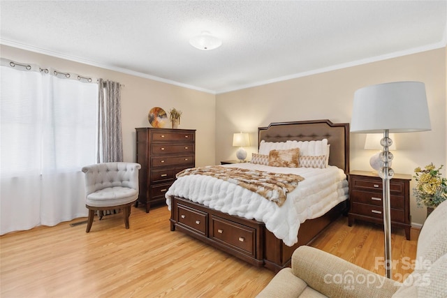 bedroom featuring crown molding, light wood-style flooring, and a textured ceiling