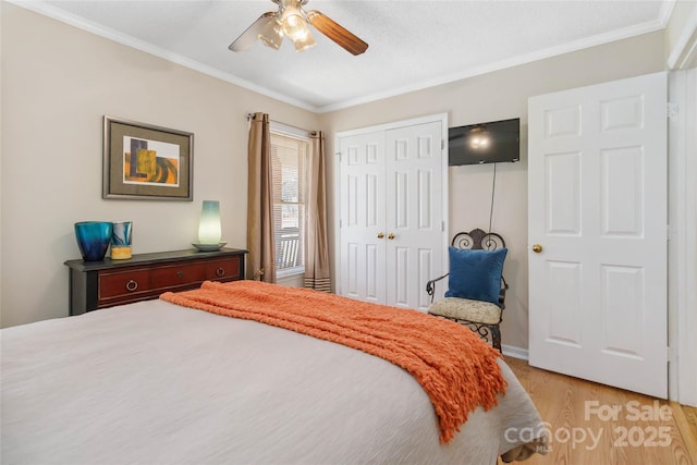 bedroom with a closet, light wood-style flooring, crown molding, and a ceiling fan