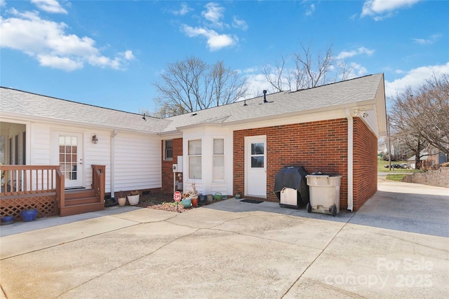 back of house featuring brick siding, a shingled roof, a deck, crawl space, and a patio