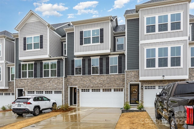 multi unit property featuring board and batten siding, a garage, stone siding, and driveway