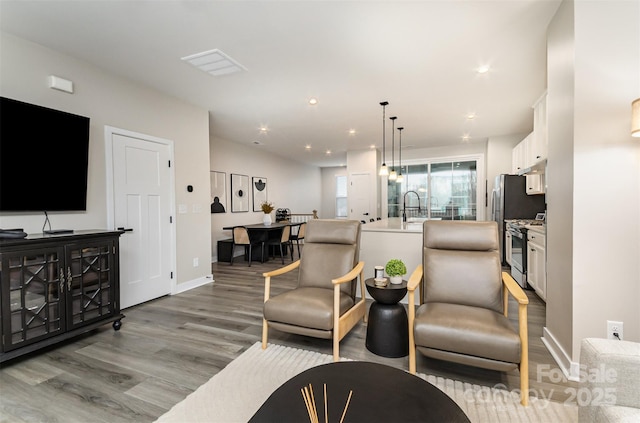 living room featuring recessed lighting, wood finished floors, and baseboards