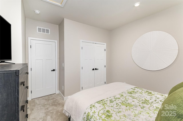 bedroom featuring baseboards, visible vents, light carpet, and a closet