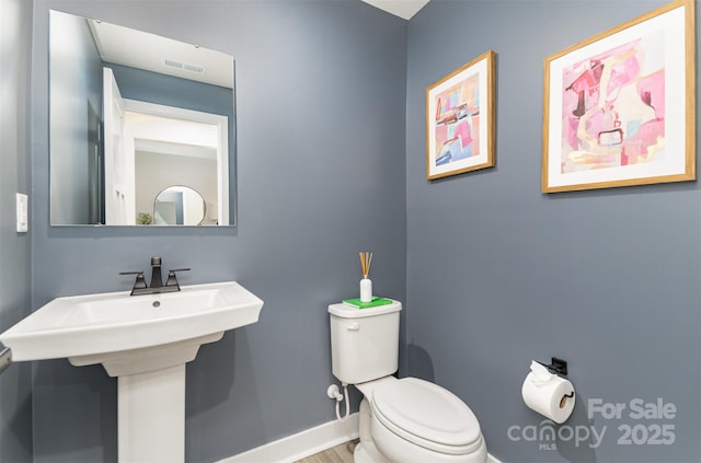 bathroom featuring toilet, visible vents, baseboards, and a sink