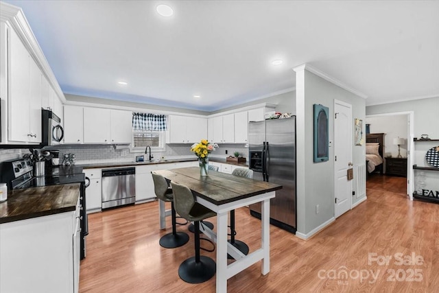 kitchen with light wood-style flooring, white cabinets, and stainless steel appliances