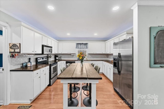 kitchen with white cabinetry, dark countertops, light wood finished floors, and stainless steel appliances