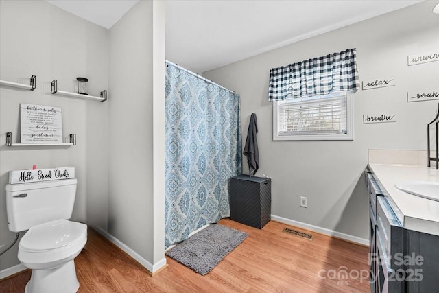 bathroom with vanity, toilet, wood finished floors, and visible vents