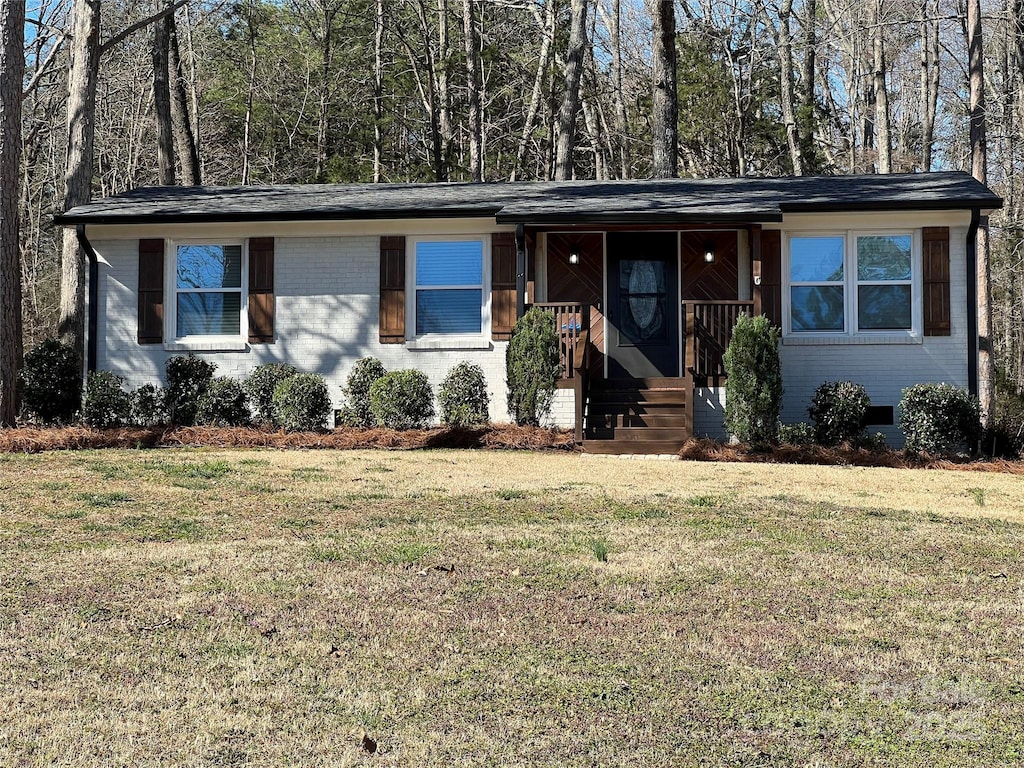 view of front of home with brick siding, covered porch, and a front lawn