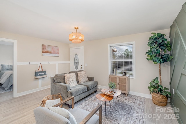 living area featuring a chandelier, baseboards, and light wood-style floors