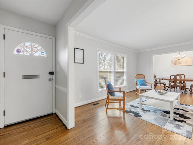 entrance foyer with crown molding, wood finished floors, baseboards, and visible vents