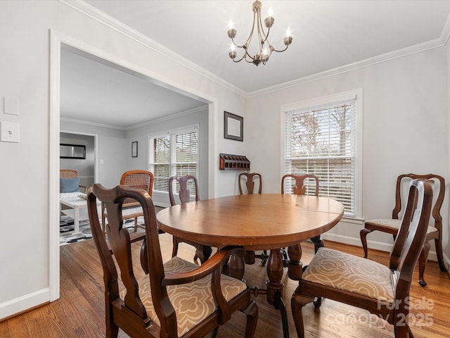 dining room with a notable chandelier, light wood-style floors, baseboards, and ornamental molding