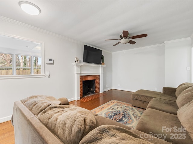 living area featuring a fireplace, crown molding, wood finished floors, and baseboards