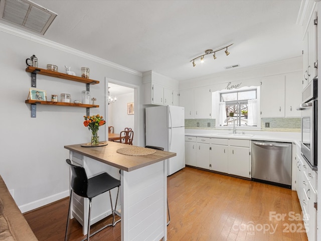 kitchen with a sink, visible vents, light wood finished floors, and stainless steel appliances