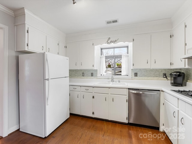 kitchen featuring visible vents, a sink, freestanding refrigerator, decorative backsplash, and dishwasher