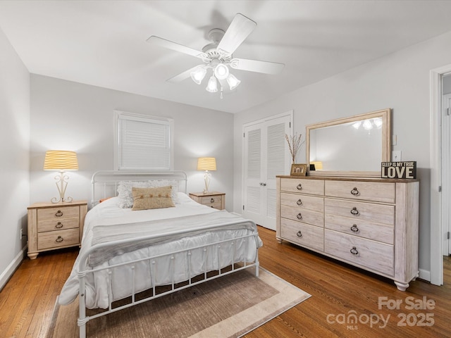 bedroom featuring a ceiling fan, wood finished floors, a closet, and baseboards