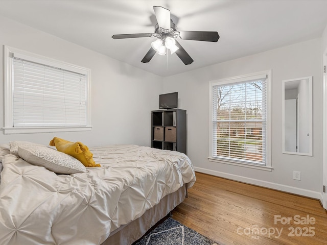 bedroom featuring a ceiling fan, baseboards, and wood finished floors