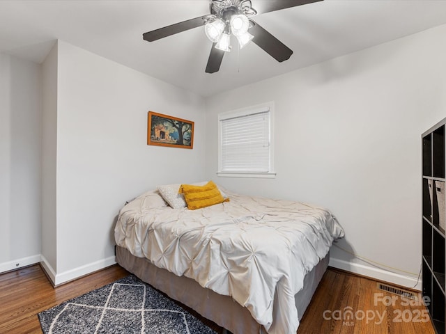 bedroom with visible vents, baseboards, wood finished floors, and a ceiling fan