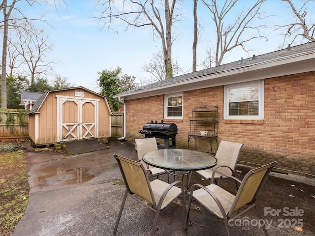 view of patio / terrace featuring fence, a shed, an outdoor structure, outdoor dining space, and area for grilling