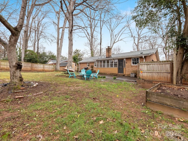 view of yard with a vegetable garden, a fenced backyard, and a sunroom