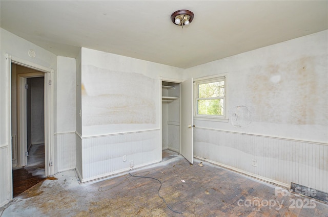 unfurnished bedroom featuring a wainscoted wall