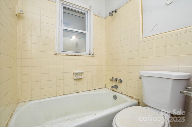 bathroom featuring tile walls, toilet, and a tub to relax in