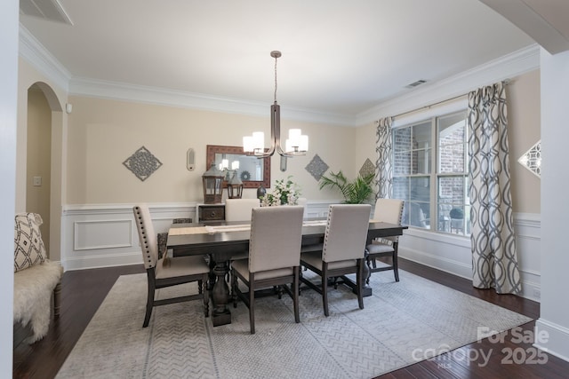 dining area with wood finished floors, visible vents, arched walkways, crown molding, and a notable chandelier