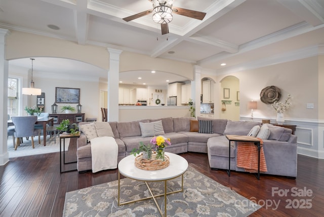 living area featuring beamed ceiling, coffered ceiling, wainscoting, and dark wood-style flooring