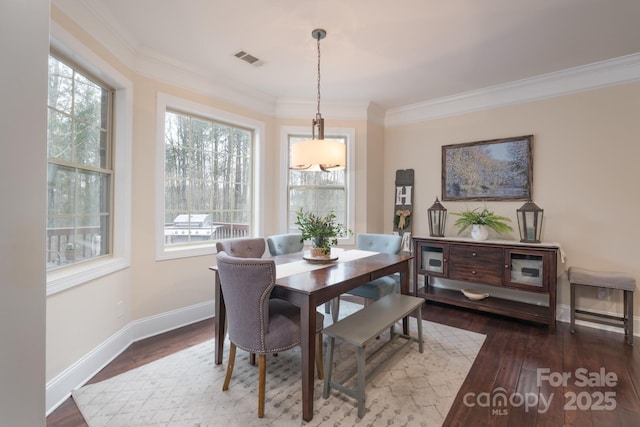 dining space with visible vents, baseboards, wood finished floors, and crown molding