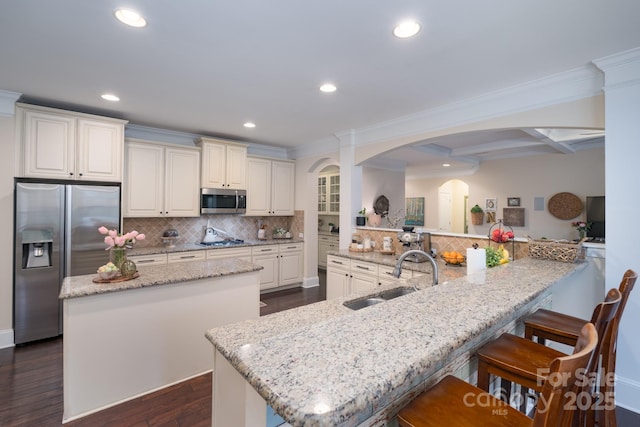 kitchen featuring backsplash, a kitchen island, recessed lighting, appliances with stainless steel finishes, and a sink