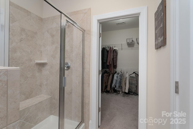 bathroom with visible vents, a stall shower, and a walk in closet