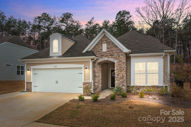 view of front of home featuring stone siding, an attached garage, and concrete driveway