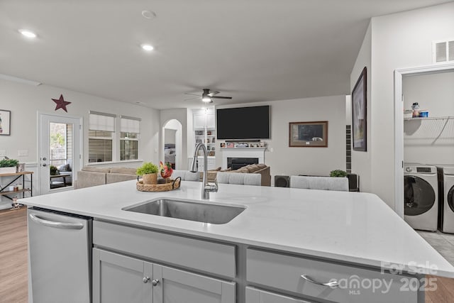 kitchen featuring washer and clothes dryer, open floor plan, arched walkways, and a sink