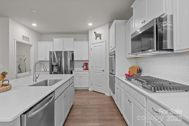 kitchen featuring a sink, stainless steel appliances, visible vents, and white cabinetry