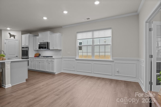 kitchen featuring visible vents, white cabinetry, stainless steel appliances, light wood-style floors, and light countertops