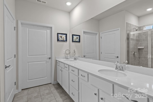 full bath with a shower stall, double vanity, tile patterned floors, and a sink